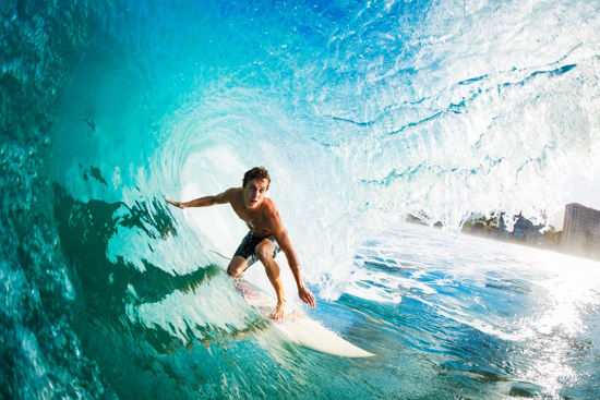 Ein Surfer in der mitte einer großen Welle umgeben von blauen Wasser
